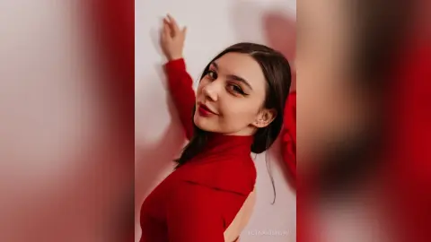 Elegant woman in a red long-sleeve turtleneck posing against a white wall with a moody, sophisticated vibe.