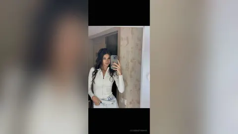 CatherineThomase — CatherineThomase takes a mirror selfie wearing a white long-sleeve top and light blue jeans.