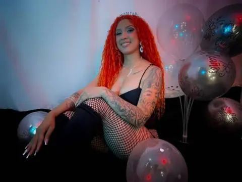 Redheaded woman in black lingerie and fishnets celebrating a birthday with silver balloons in a moody setting.