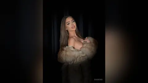 Glamorous woman in a luxurious faux fur coat posing against a dark backdrop for a moody, high-fashion look.
