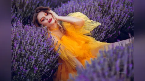 AmelieSkylar reclines in a field of purple lavender wearing a bright yellow ruffled tulle dress.