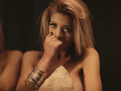 Moody portrait of a blonde woman in a white fuzzy top wearing stacked silver bangles against a dark background.