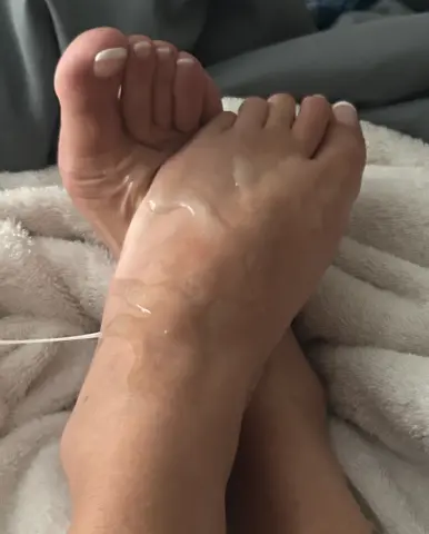 Close-up of bare feet resting on a soft white textured blanket in a cozy, relaxed indoor setting.
