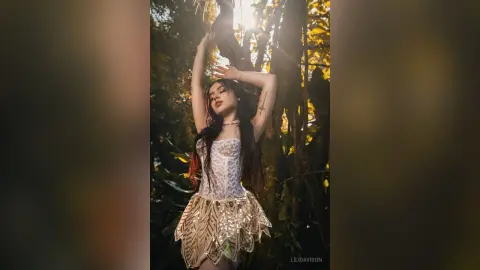 Dreamy portrait of a woman in a white sequined outfit posing under sunlight in a lush green forest.