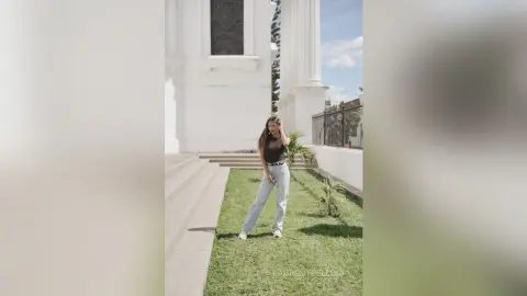 LaurentBelluci stands on a green lawn wearing a black tank top and light blue jeans.
