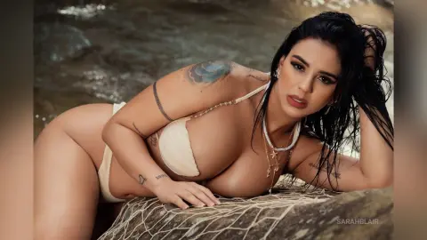 Curvy woman in a white bikini relaxing on a rocky beach with a serene summer mood.