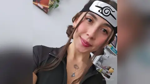 RossiNoleen smiles wearing a black headband and a black zip-up top with a silver necklace.