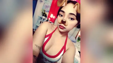 Young woman in a red and white halter top posing indoors with a playful dog filter expression.