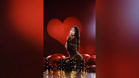 Glamorous woman in white lingerie posing by a large heart decoration and LOVE sign for a romantic Valentine's theme.