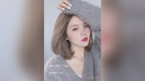 Young woman in a cozy grey sweater posing with a soft, dreamy expression in a minimalist setting.