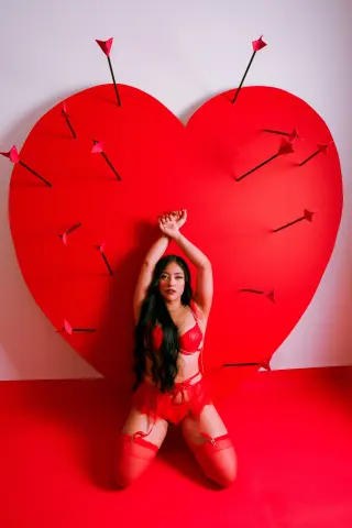 Nicol_Pierce poses in red lingerie and stockings against a large red heart background with arrows.