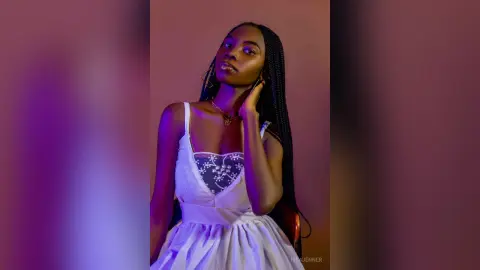 Elegant Black woman in a white sundress posing with a moody, cinematic glow in a studio setting.
