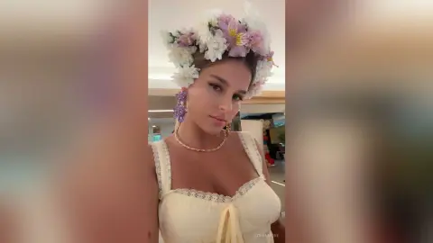 Beautiful woman in a cream lace dress and floral crown posing with a dreamy, ethereal aesthetic.