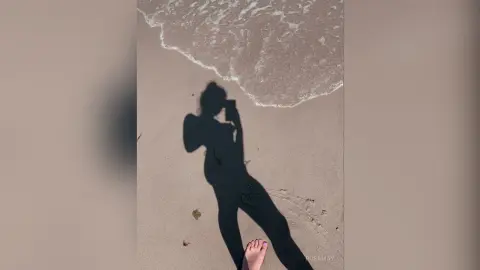 RosaMay casts a long shadow on the sand next to the ocean waves.