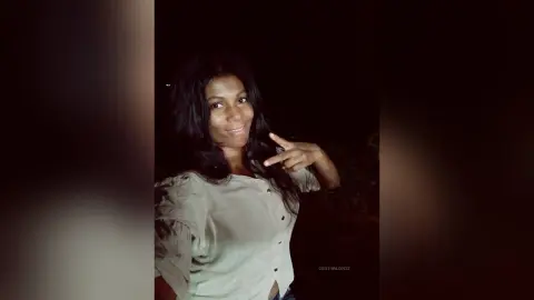Smiling woman in a white blouse posing outdoors at night with a joyful mood.