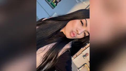 AriaVex pouts her lips while looking at the camera with long, straight black hair.