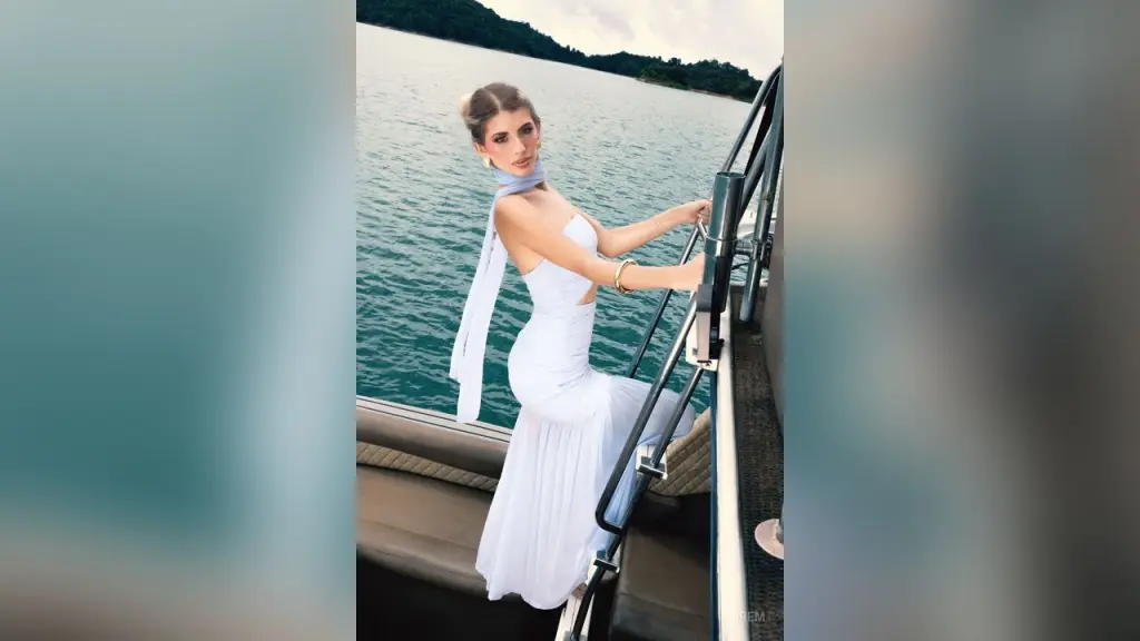 Irem โ Irem poses on a boat in a white sleeveless dress, leaning against the metal railing over the blue water.