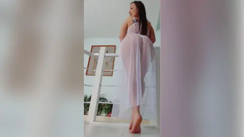 TannySmith poses in a sheer white nightgown, showing off her curves and bare feet while standing by a white railing.
