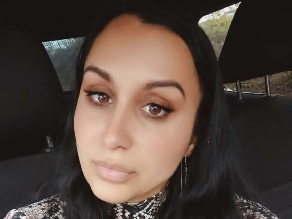 Close-up portrait of a woman with long dark hair and natural makeup sitting in a car.