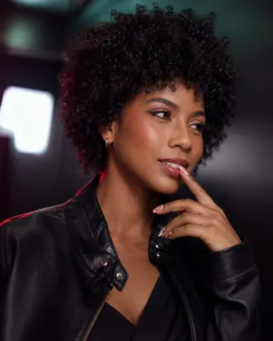 KylieDecks — KylieDecks wears a black leather jacket and looks off to the side with her finger touching her lip.