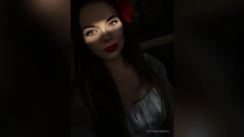 Moody portrait of a woman with red lips and dark hair in dramatic low-light shadows.