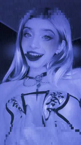 Smiling blonde woman in a black lace corset top posing in a moody blue-toned aesthetic setting.