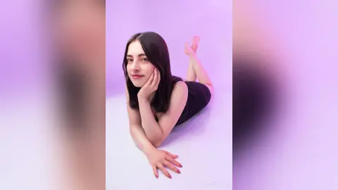 Smiling young woman in a black top relaxing on a lavender background with a peaceful mood.