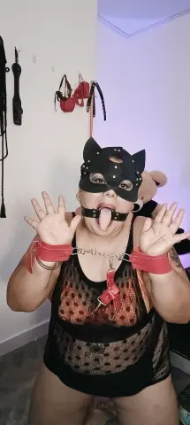 Woman in black cat mask and red lingerie playing with hands in a bedroom setting.