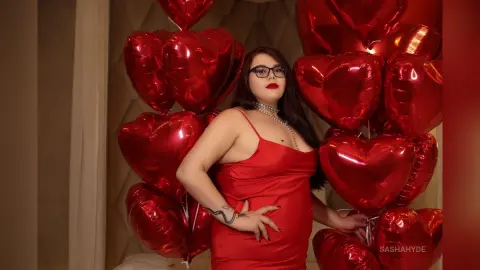 Glamorous woman in a red dress posing with red heart balloons for a romantic Valentine's Day celebration.