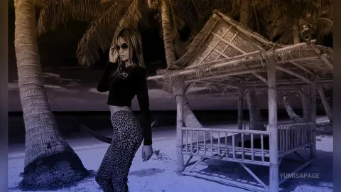 Stylish woman in black crop top and leopard print leggings posing by a tropical beach hut at sunset.