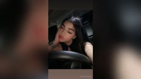 Young woman with long dark hair in a black top relaxing inside a car with a moody, cinematic aesthetic.