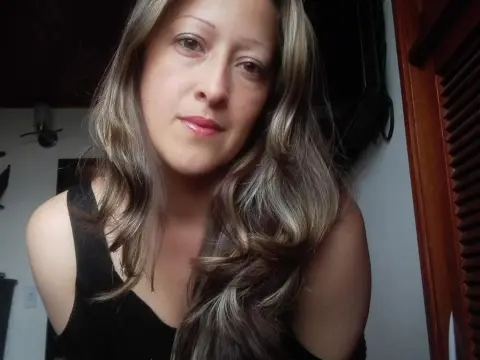 Gaby_Sexy — Gaby_Sexy looks into the camera with long wavy hair while wearing a black tank top.