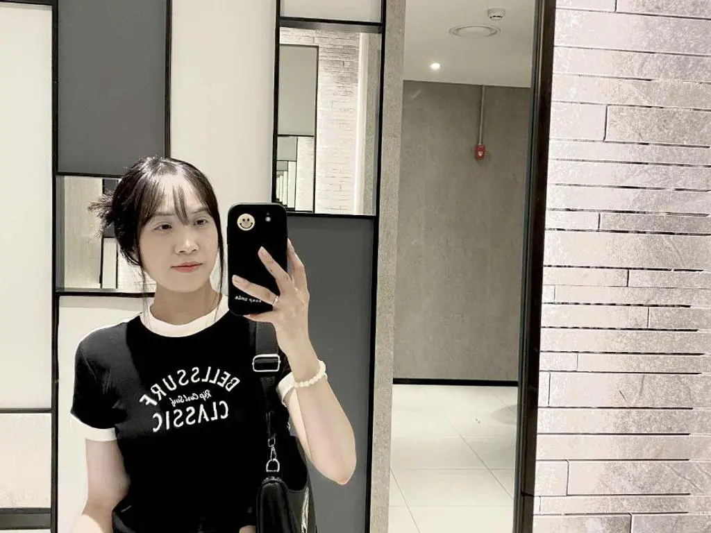 Lamapp69 poses for a mirror selfie wearing a black t-shirt with white text, holding a black phone and looking at the camera.