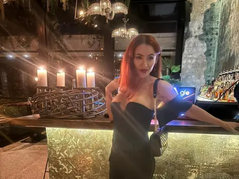 Diamond_Slutty — Elegant woman in a black cocktail dress posing at a moody, candlelit upscale bar at night.