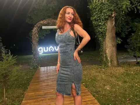 Diamond_Slutty — Redheaded woman in a denim midi dress standing on a wooden path in a garden at night.