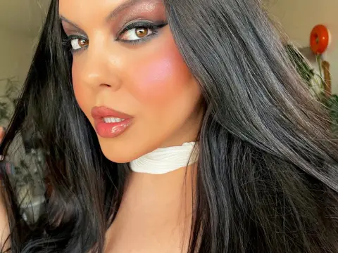 PrincesssAnisia with long dark hair and heavy makeup poses closely for a selfie wearing a white choker.