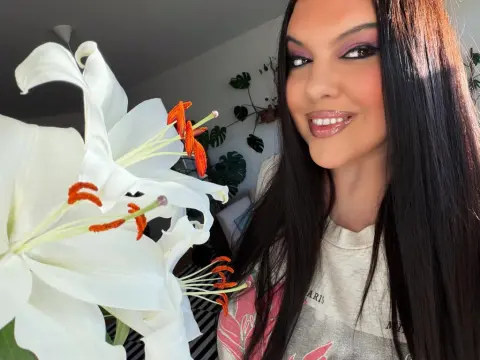 PrincesssAnisia — PrincesssAnisia smiles while holding a large white lily close to her face in a bright room.