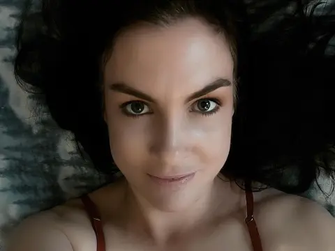 Close-up portrait of a smiling woman with dark hair lying down in a relaxed, cozy mood.