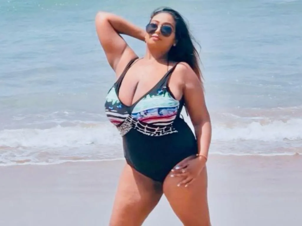 princesSsandy — princesSsandy poses in a colorful patterned swimsuit and sunglasses on a sunny beach.