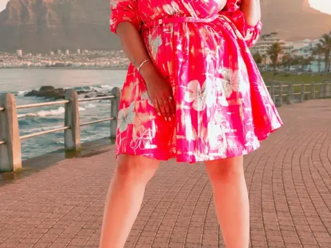 princesSsandy — princesSsandy stands on a seaside boardwalk wearing a bright pink floral sundress.