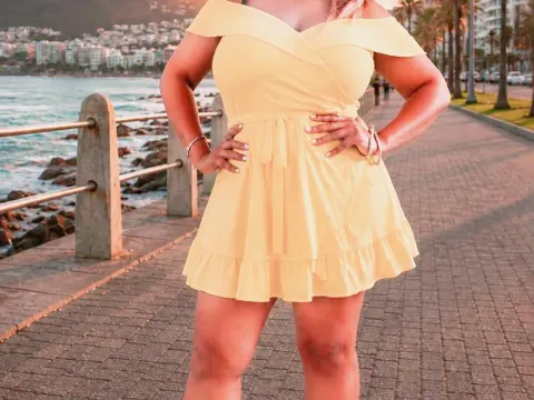 princesSsandy — princesSsandy stands on a seaside boardwalk wearing a short yellow sundress.