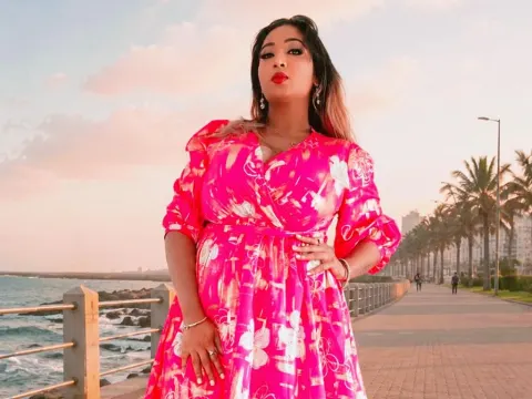 princesSsandy — princesSsandy wears a pink floral dress while posing on a seaside walkway at sunset.