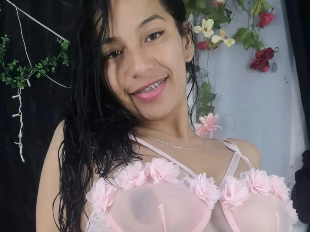 YasmineD749 smiles close-up, showing her long black hair and dark eyes while wearing a black top.