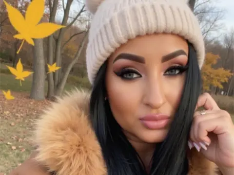 Woman with glamorous makeup wearing a cozy beige beanie and faux fur coat in an autumn park setting.