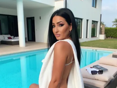 Beautiful woman in a white towel relaxing by a luxury swimming pool at a sunny villa.