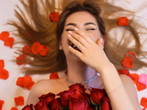 Laughing woman lying in hair and red rose petals wearing a silver necklace for a romantic mood.