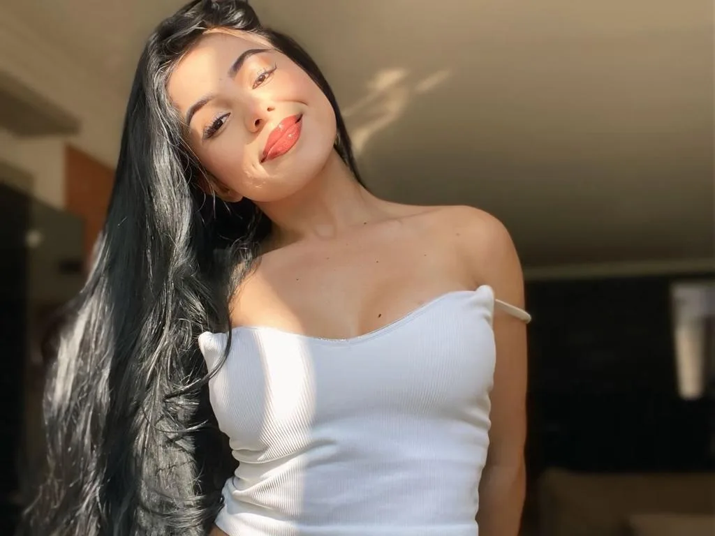 EmmaWoodL — EmmaWoodL smiles at the camera while wearing a white tube top and showing off her long black hair.