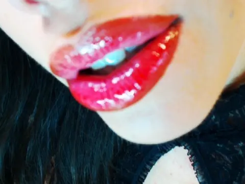 QueenOfLust — Close-up of a woman with glossy red lipstick and dark hair wearing a black lace outfit for a glamorous look.