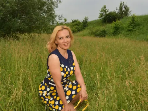 KateConner wearing a blue and yellow polka dot dress while sitting in a grassy field.