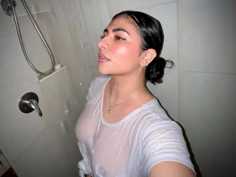 LyssaSunnyy — LyssaSunnyy poses in a shower wearing a wet, sheer white t-shirt that shows her breasts.